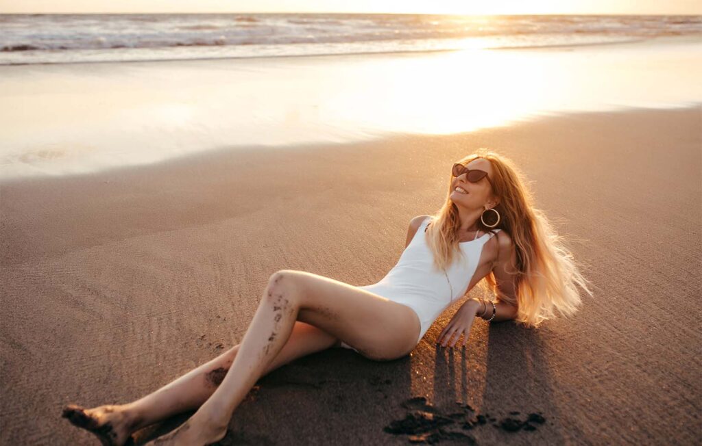 Woman wearing white swimsuit tanning safely on Singapore beach