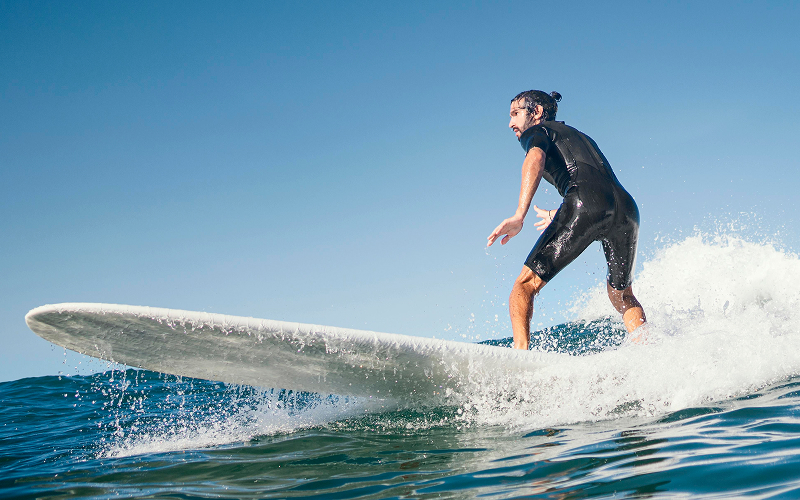 Man surfing on a wave wearing a black wetsuit.