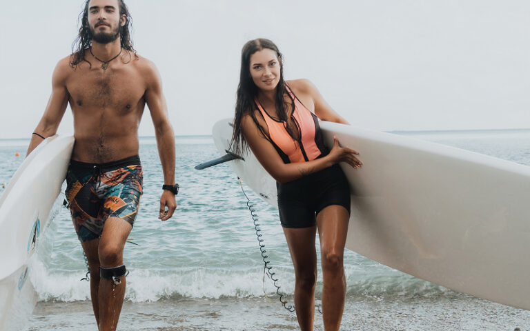Surfers walking on beach in performance-focused swimwear materials.